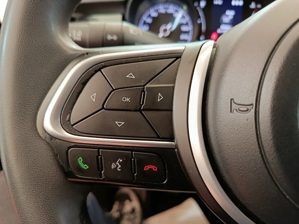 Gros plan sur les commandes multifonctions du volant noir du Fiat 500X 2020, avec boutons appel et navigation.