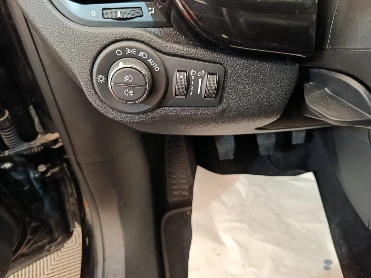 Gros plan sur les commandes d’éclairage et réglages du tableau de bord côté conducteur d’une Fiat 500X blanche.