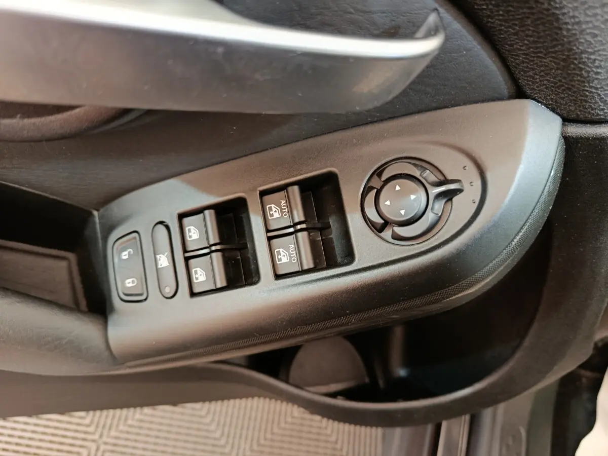 Gros plan sur les commandes de lève-vitres et réglage des rétroviseurs côté conducteur d'une FIAT 500X blanc.