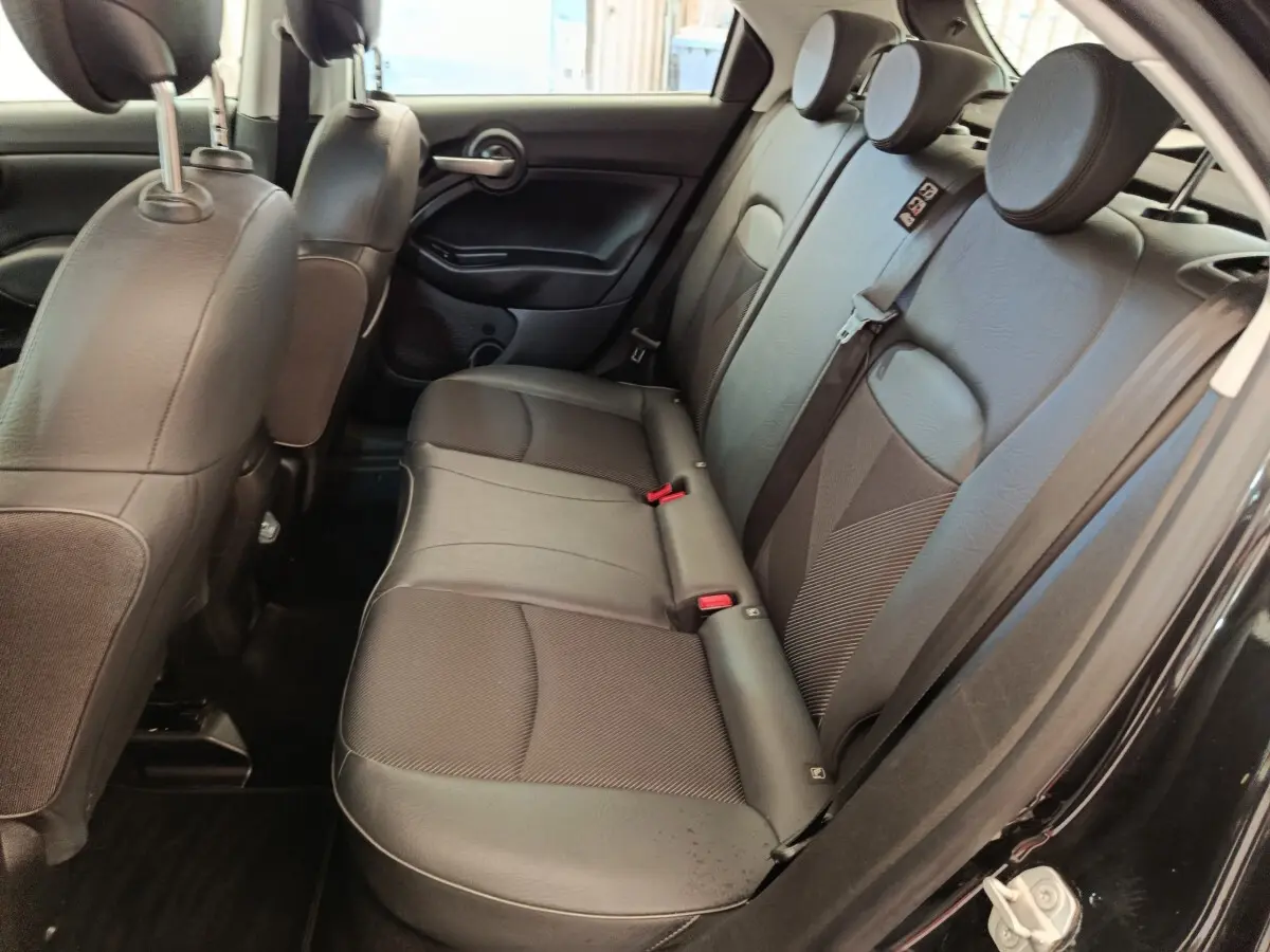 Vue intérieure côté droit des sièges arrière noirs en cuir et tissu d'une Fiat 500X 2020, porte ouverte.