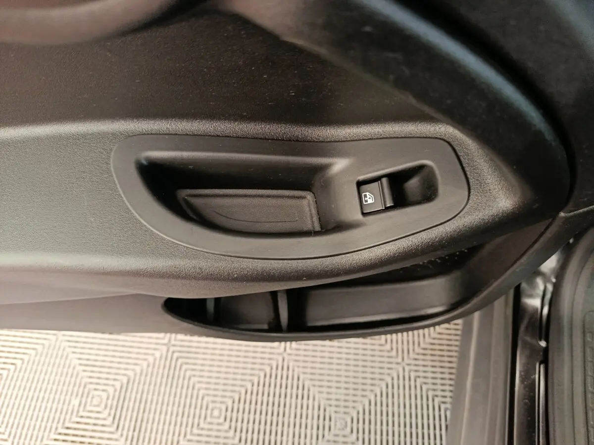 Gros plan sur la poignée intérieure noire et le bouton de verrouillage de la porte côté conducteur d'une FIAT 500X blanche.