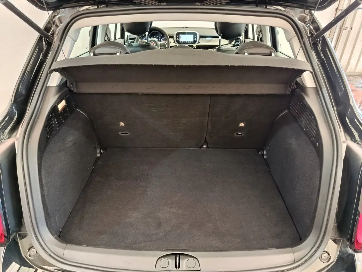 Coffre ouvert vu de l'arrière d'une FIAT 500X noire avec banquette arrière et tableau de bord visibles.