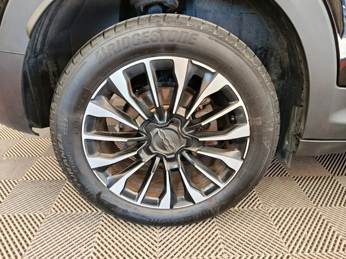 Gros plan sur la roue avant droite d'une FIAT 500X blanche, avec jante alliage et pneu Bridgestone.