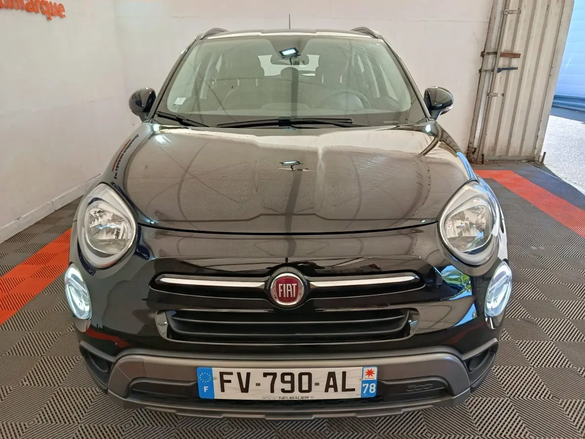Vue avant d'un FIAT 500X noir avec phares ronds allumés et calandre chromée dans un garage.