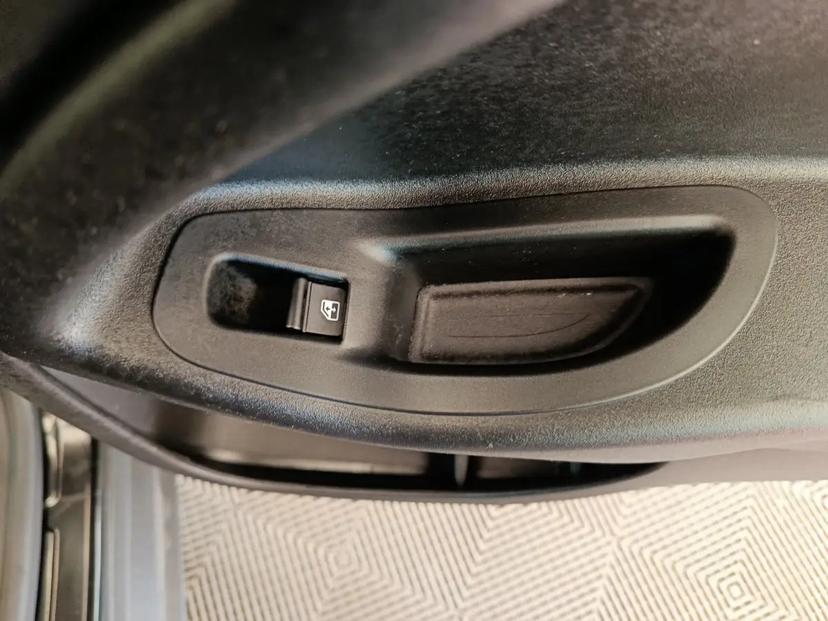 Gros plan sur le bouton de commande de la vitre électrique côté conducteur d'une Fiat 500X blanche.