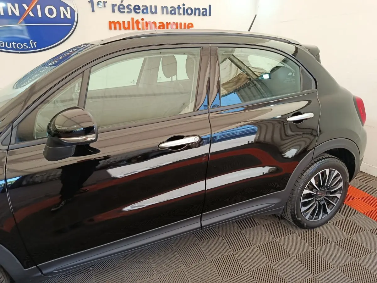 Vue latérale droite d'une FIAT 500X noire avec jantes alliage et rétroviseurs assortis.