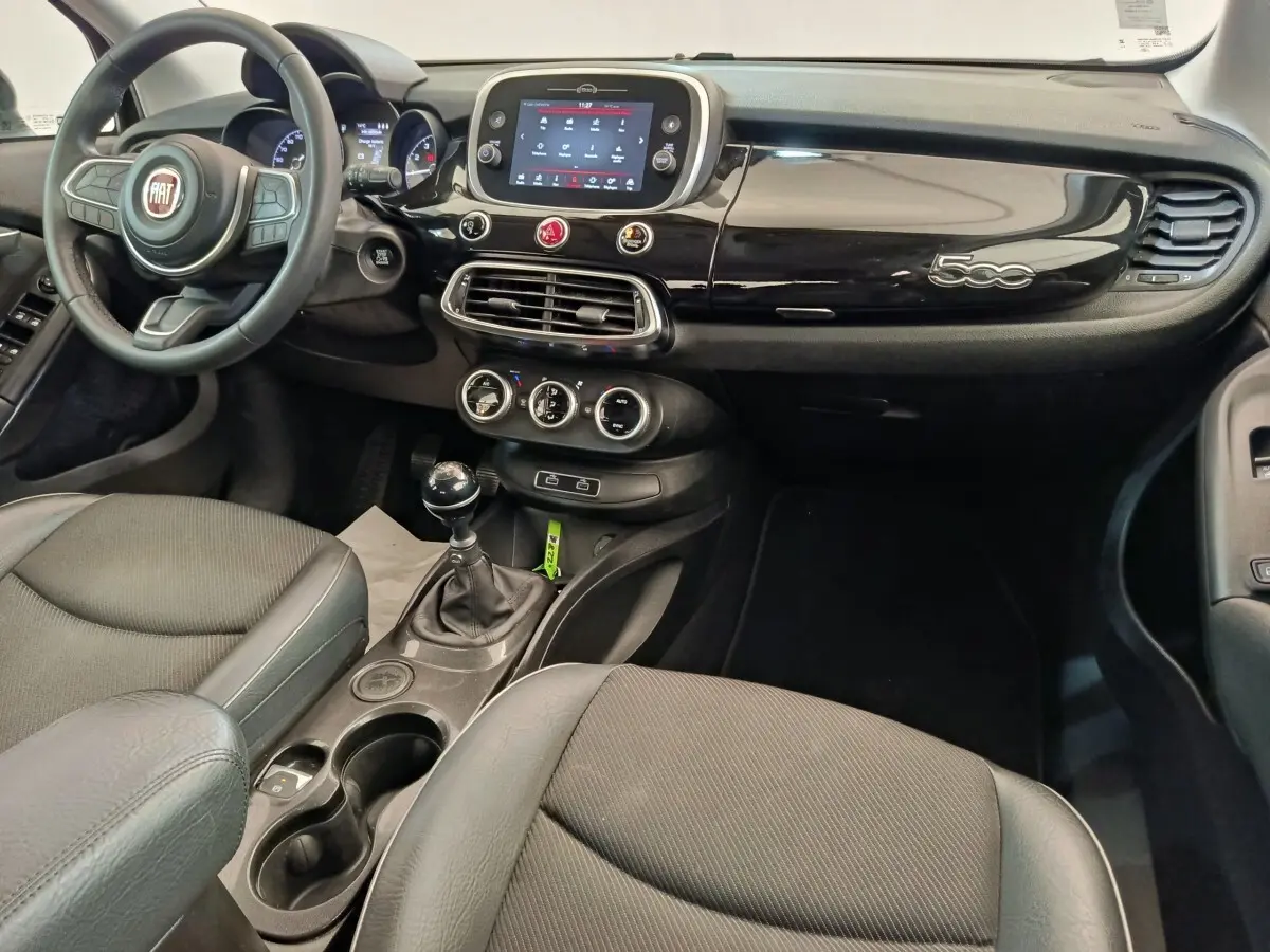 Vue intérieure avant droite du tableau de bord noir brillant et volant cuir de la Fiat 500X 2020 avec écran tactile central.