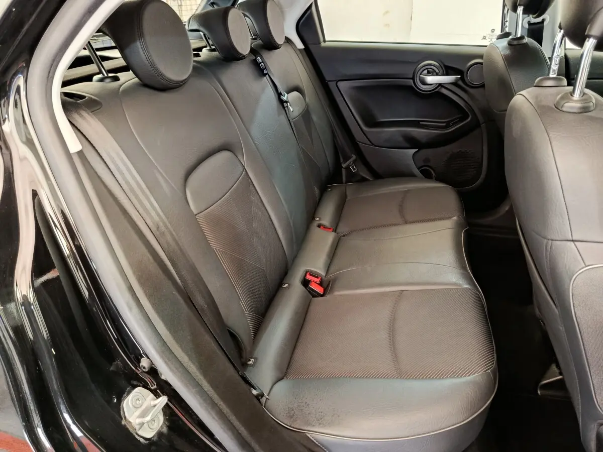 Banquette arrière en cuir noir vue côté gauche dans une FIAT 500X Cross blanche, porte ouverte.