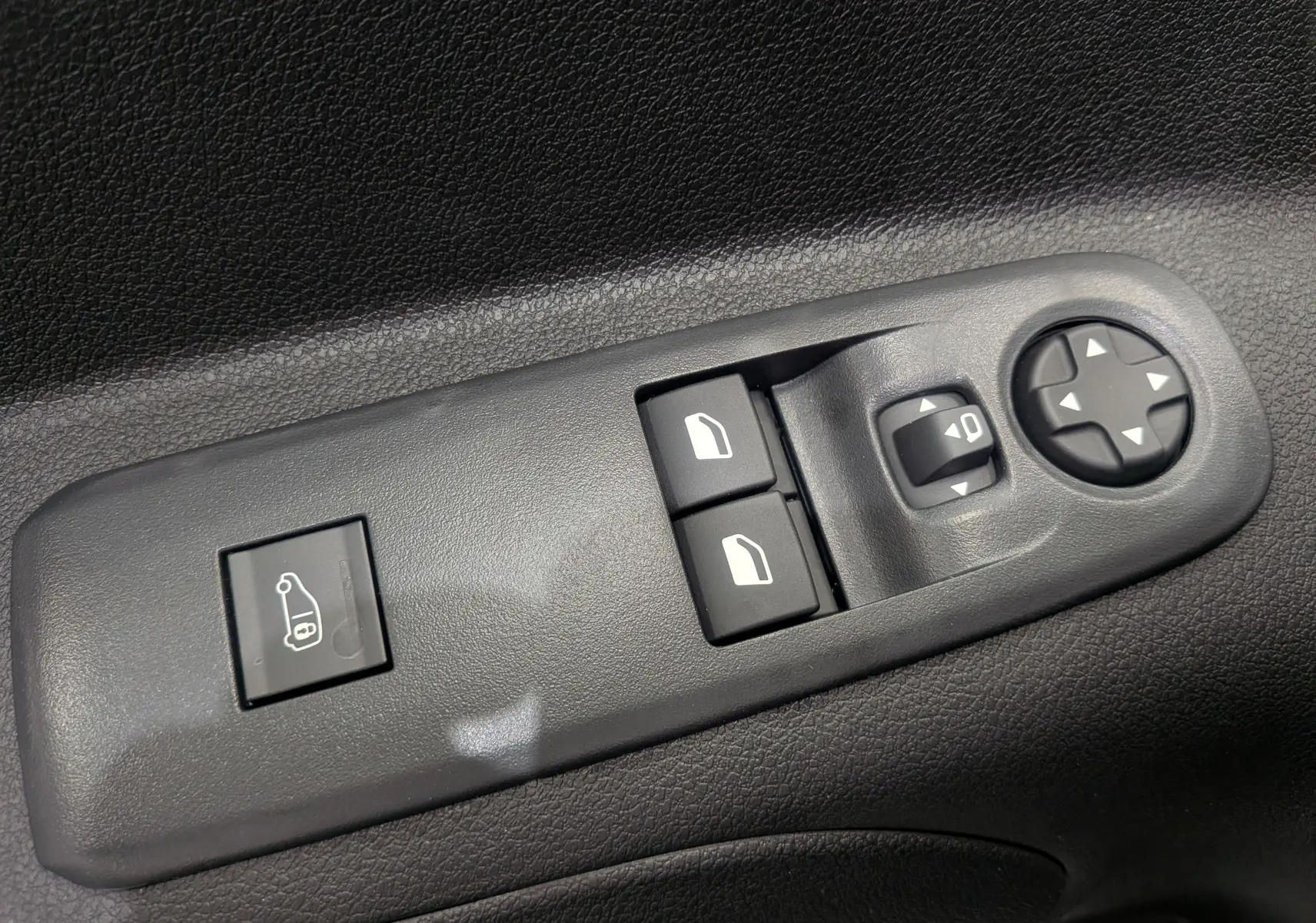 Gros plan sur les commandes de réglage des rétroviseurs et des vitres côté conducteur du Citroën Berlingo blanc 2025.