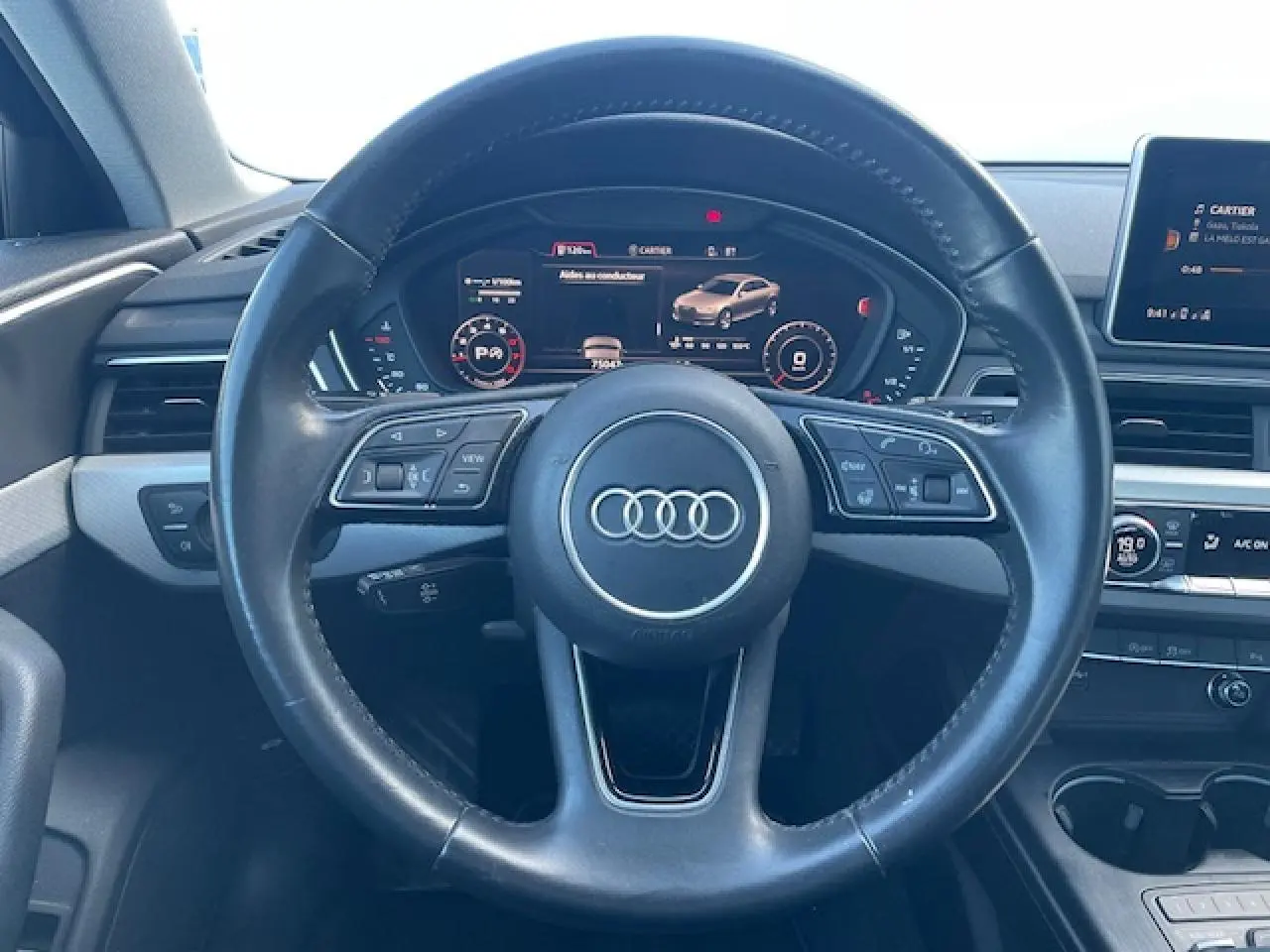Vue intérieure centrée sur le volant cuir noir multifonction de l'Audi A4 2019 avec tableau de bord numérique.