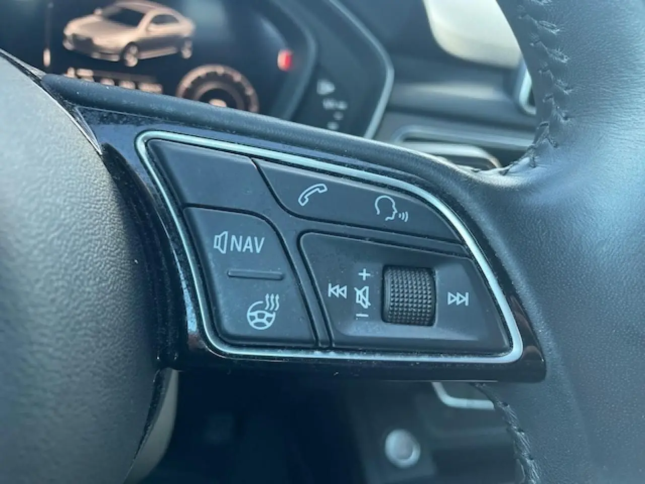 Gros plan sur les commandes audio et navigation du volant cuir noir de l'Audi A4 S line argent 2019.