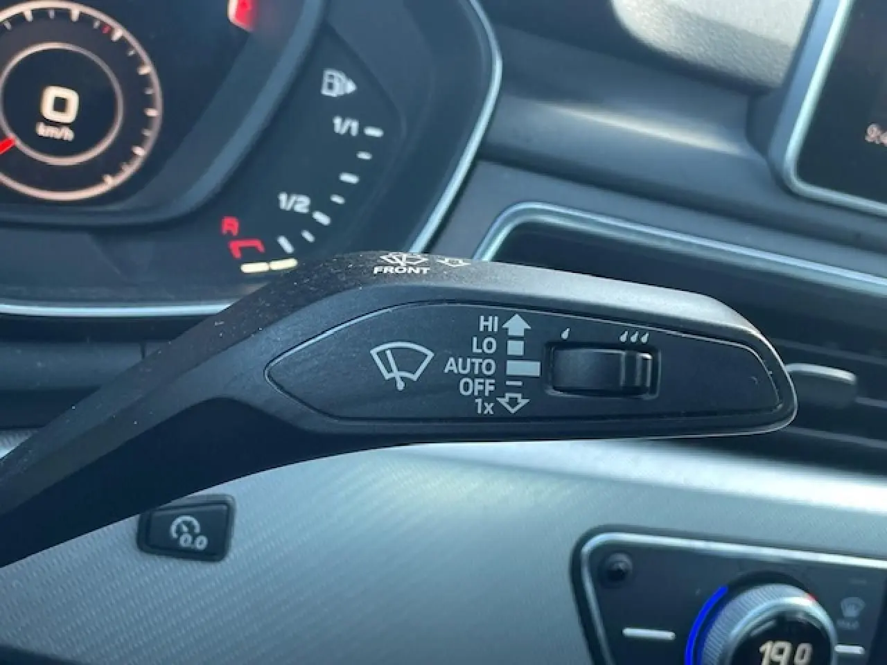 Gros plan sur la commande des essuie-glaces d'une Audi A4 argent, avec tableau de bord et console en arrière-plan.