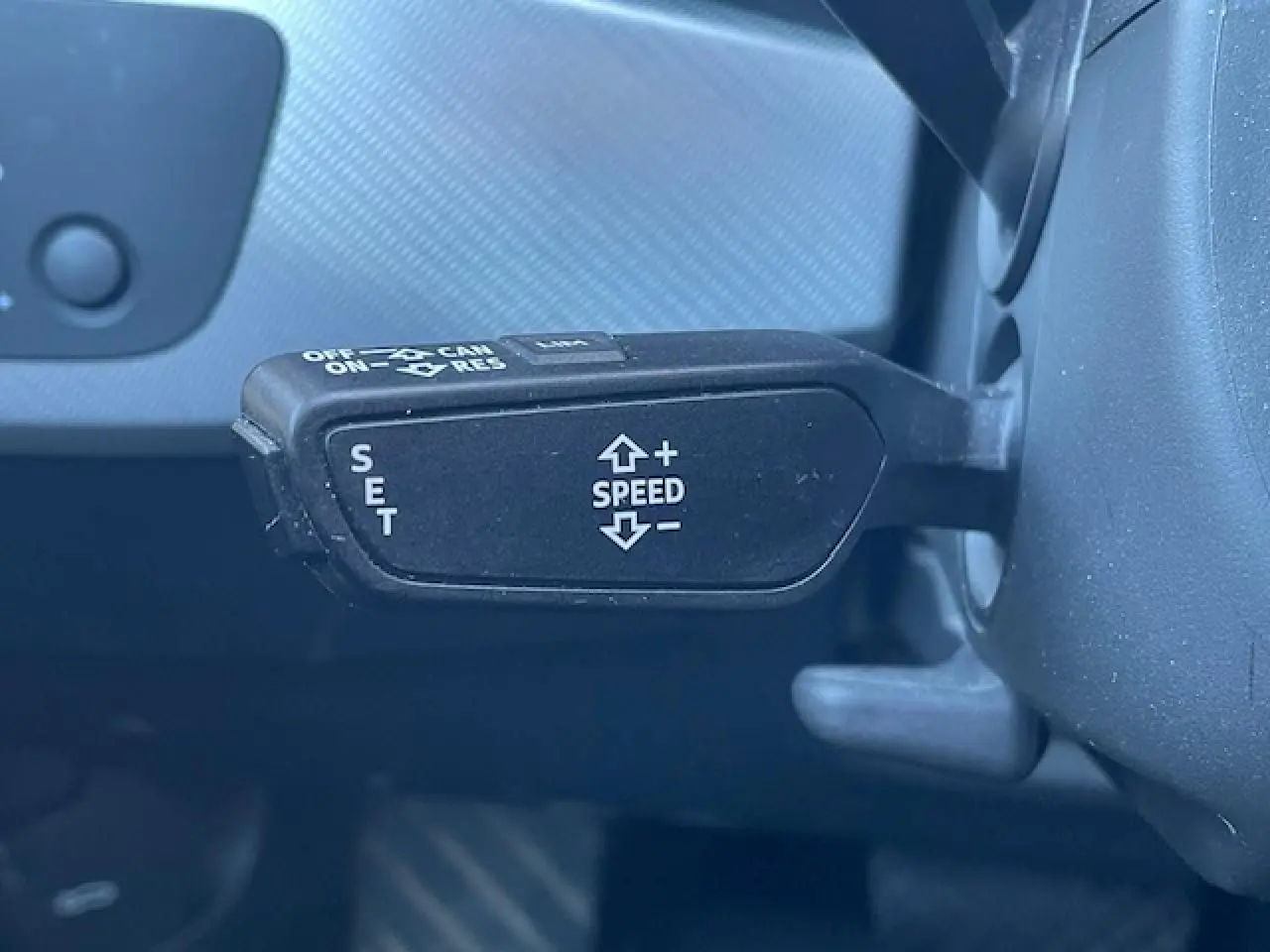 Gros plan sur la commande de régulateur de vitesse noire à gauche du volant d'une Audi A4 argent Fleuret Metal 2019.