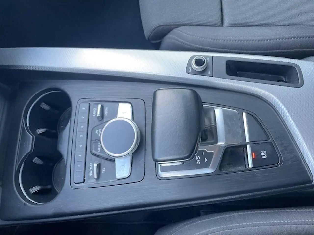 Vue plongeante sur la console centrale noire avec levier de vitesses automatique et commandes multimédia d'une Audi A4 argentée de 2019