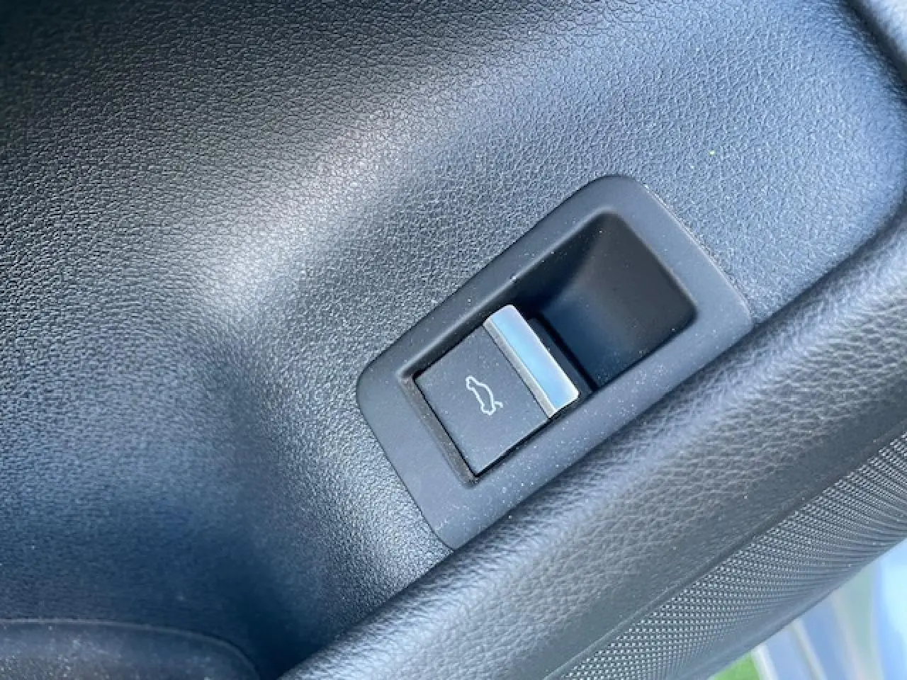 Bouton d'ouverture du coffre en plastique noir dans le coffre d'une Audi A4 argent Fleuret Metal de 2019.