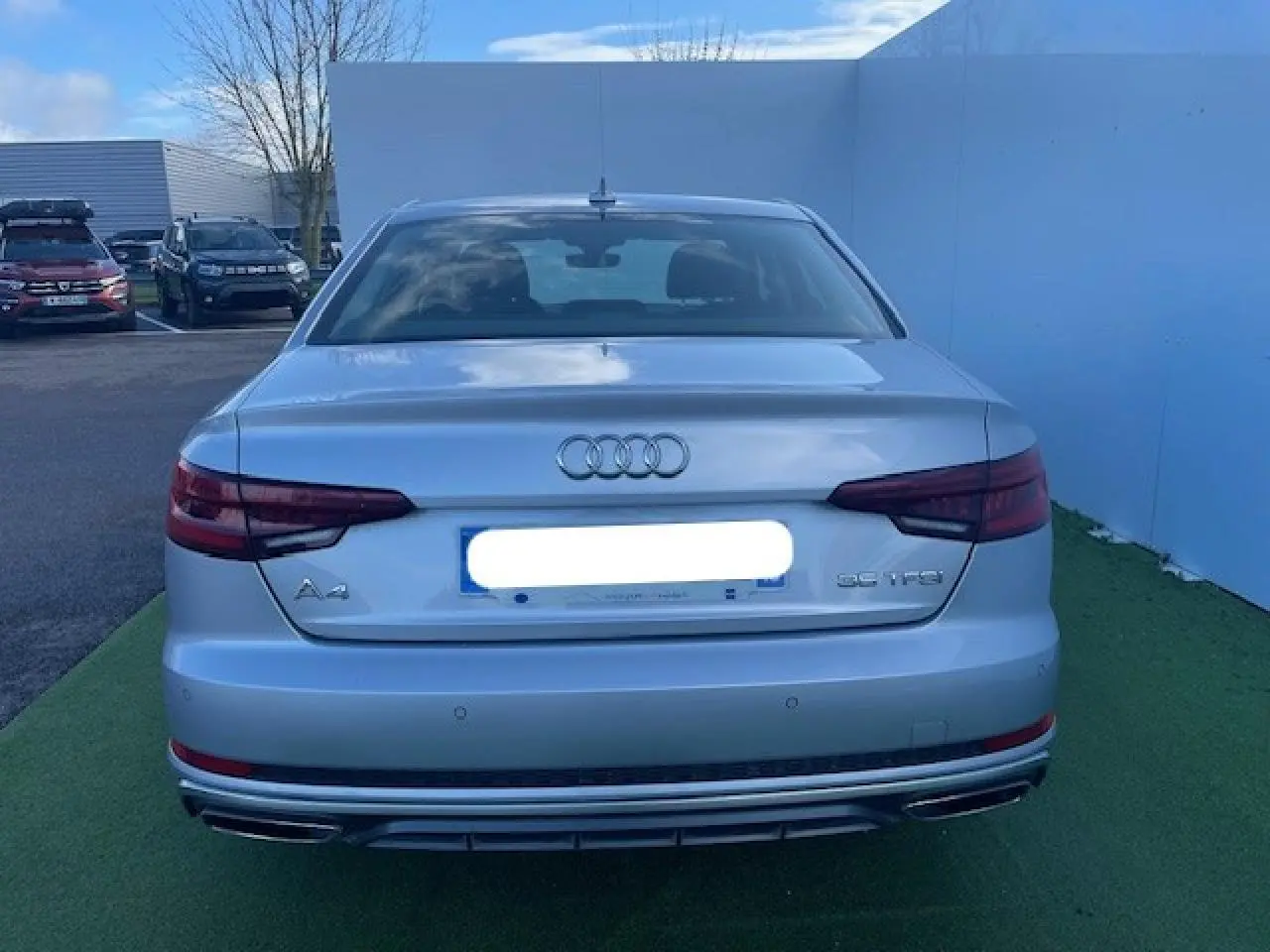 Vue arrière d'une Audi A4 argent fleuret métal avec feux arrière LED et double sortie d'échappement chromée.