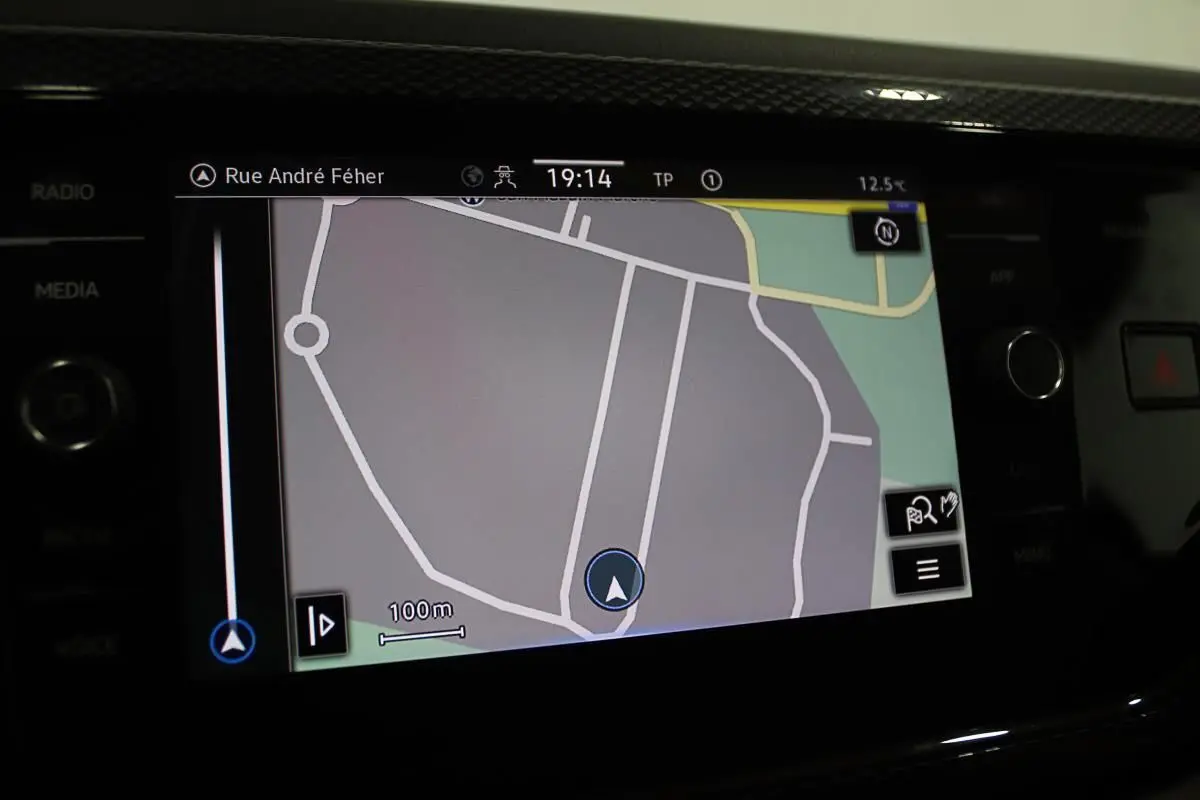 Écran de navigation GPS allumé dans l'habitacle d'une Volkswagen Polo noire, affichant une carte routière détaillée.