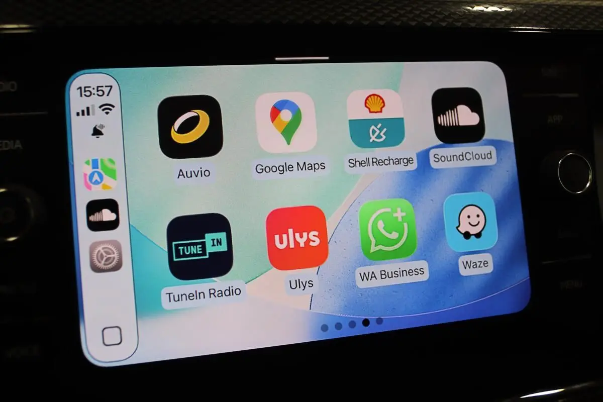 Écran tactile du système Apple CarPlay dans une Volkswagen Polo noire, affichant plusieurs applications de navigation et musique.