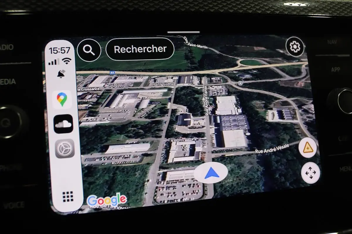 Écran tactile du système GPS Apple CarPlay dans une Volkswagen Polo noire, affichant une carte satellite détaillée.