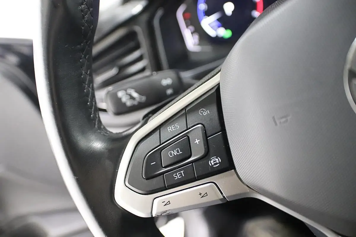 Gros plan sur les commandes au volant noir de la Volkswagen Polo 2022 avec régulateur de vitesse et finition argentée.