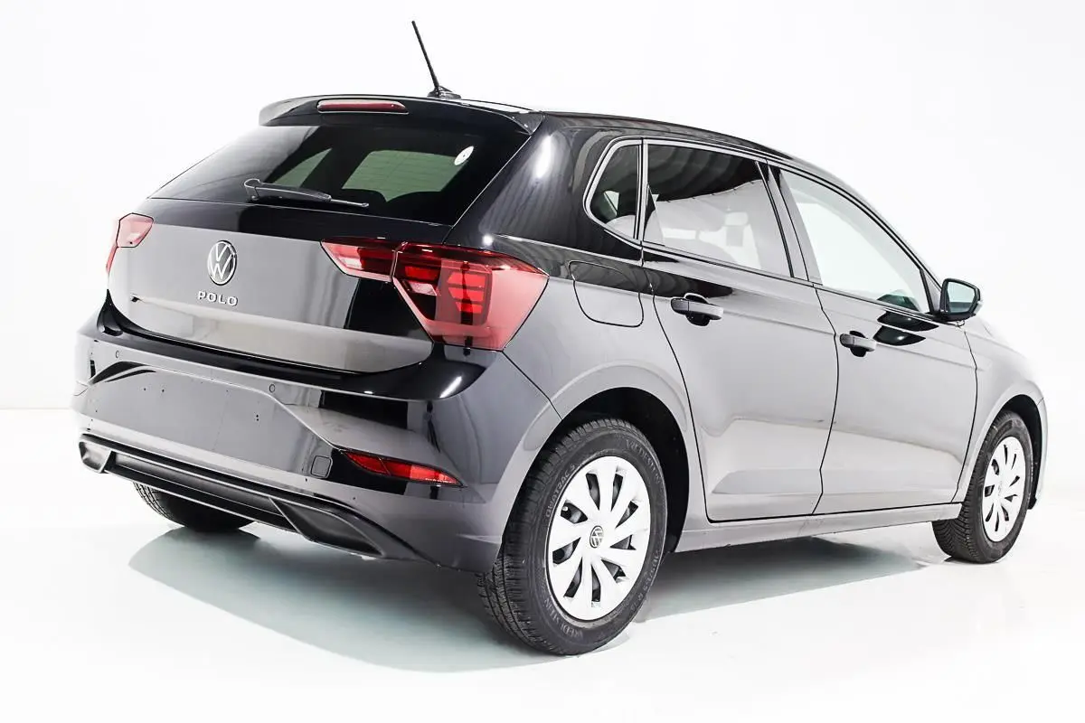 Volkswagen Polo noire vue en 3/4 arrière côté droit, avec feux arrière et jantes blanches visibles.