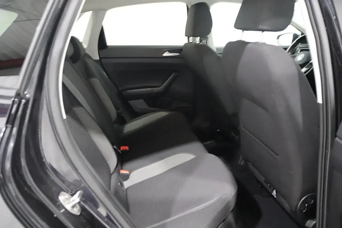 Vue intérieure montrant les sièges arrière en tissu gris et noir d'une Volkswagen Polo noire de 2022, porte arrière ouverte.