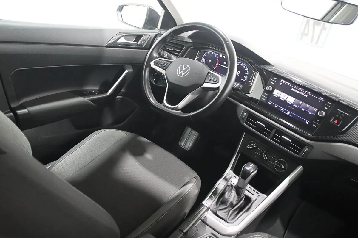 Intérieur de la Volkswagen Polo 2022 vu côté conducteur, avec volant multifonction et écran tactile allumé.