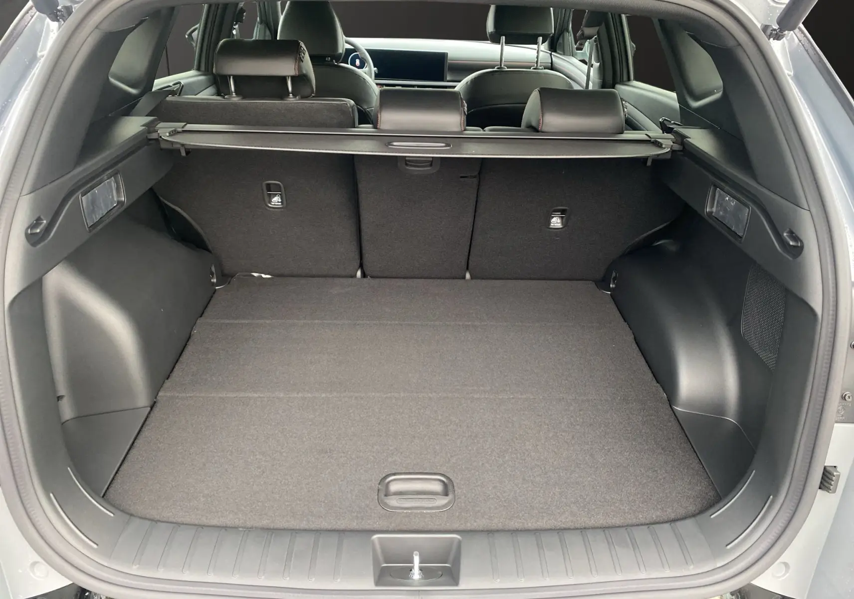 Coffre ouvert vu de l'arrière d'un Hyundai Tucson gris Shadow, avec cache-bagages et sièges arrière en cuir noir.