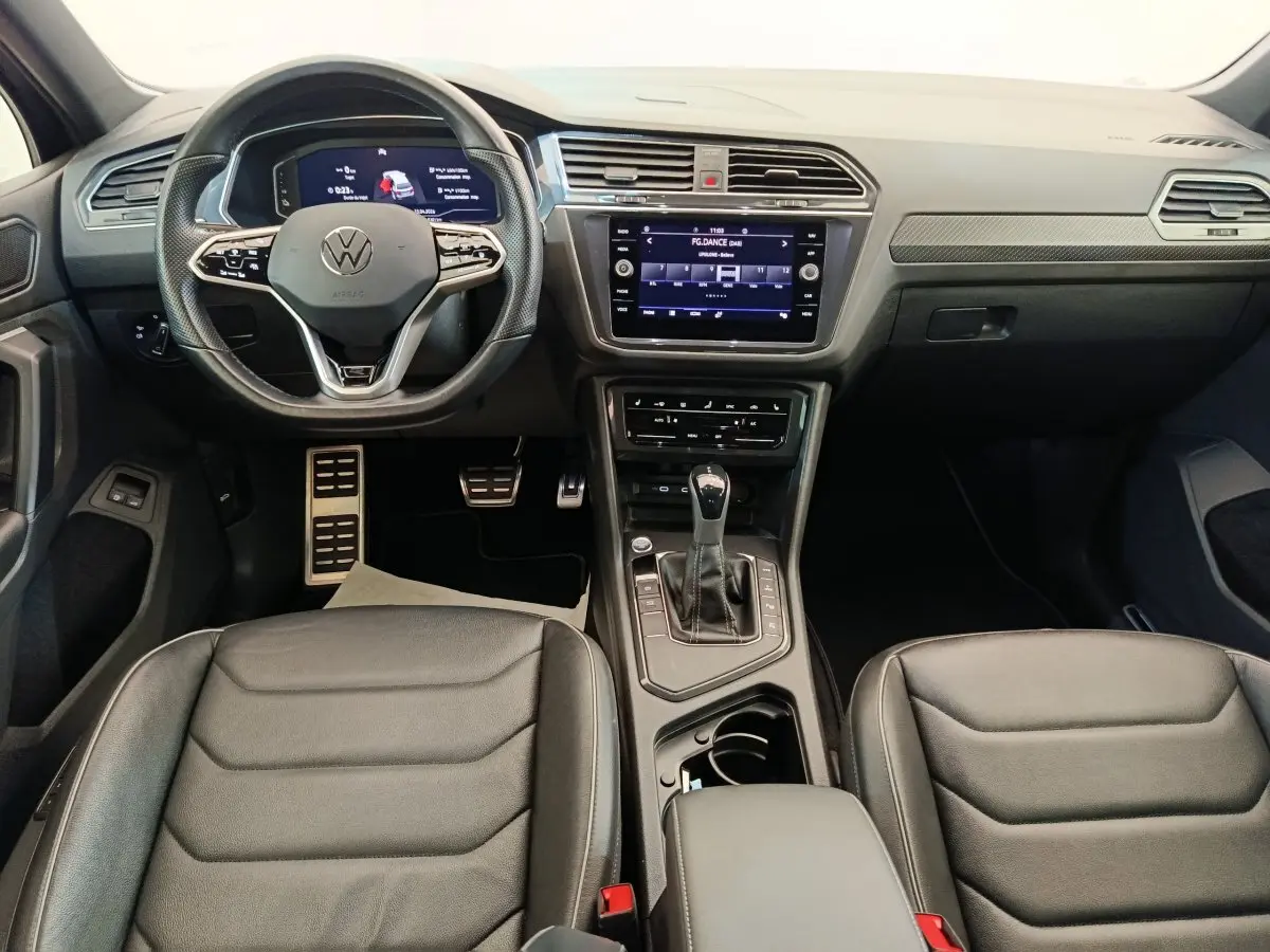 Vue intérieure avant du Volkswagen Tiguan 1.4 eHybrid 2023 avec tableau de bord numérique et sièges cuir noirs.