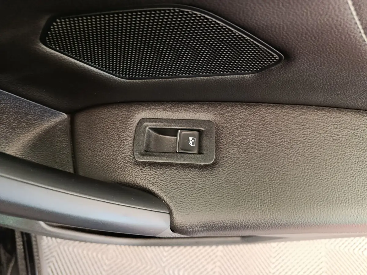Détail de la commande de lève-vitre sur la porte intérieure noire du Volkswagen Tiguan 1.4 eHybrid 2023.