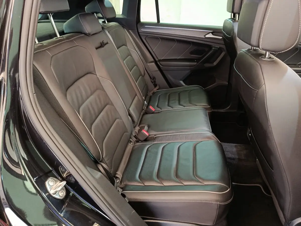 Vue intérieure côté gauche des sièges arrière en cuir noir du Volkswagen Tiguan 1.4 eHybrid 2023 avec portes ouvertes.