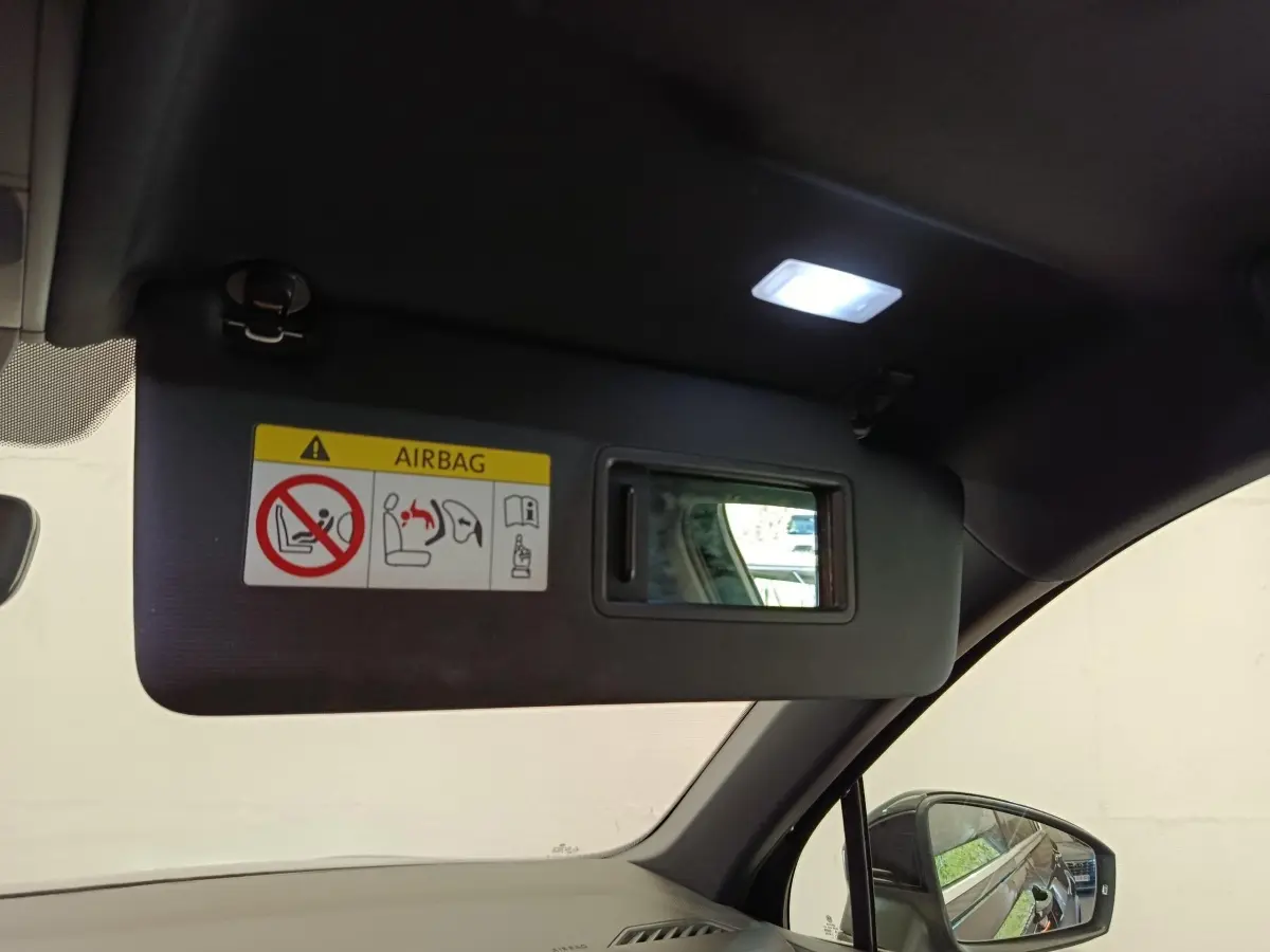 Vue intérieure du pare-soleil côté conducteur du Volkswagen Tiguan noir 2023 avec miroir et avertissement airbag.