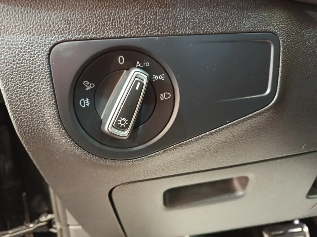 Gros plan sur la molette de réglage des phares dans l’habitacle noir du Volkswagen Tiguan 1.4 eHybrid 2023.