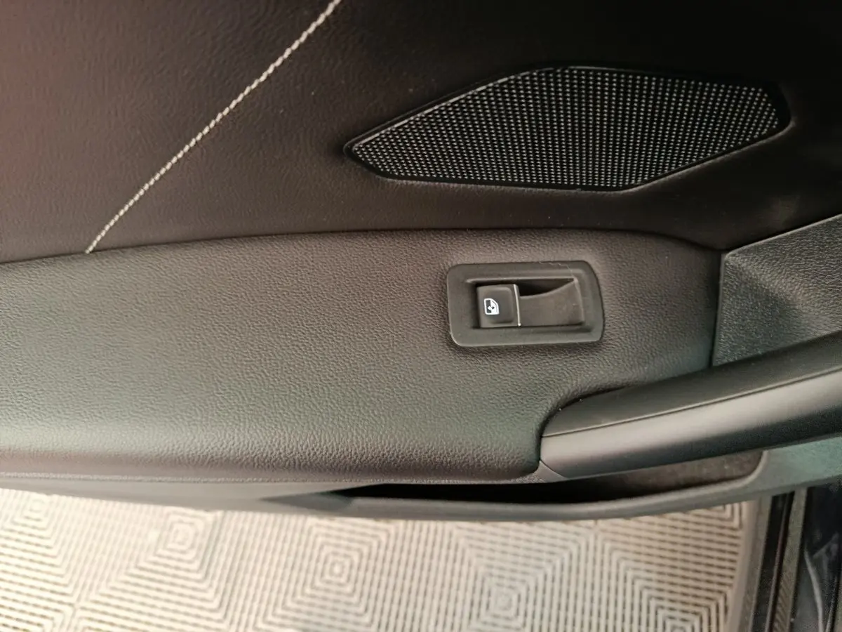 Détail de la porte intérieure côté conducteur du Volkswagen Tiguan noir, avec bouton de verrouillage et haut-parleur intégré.