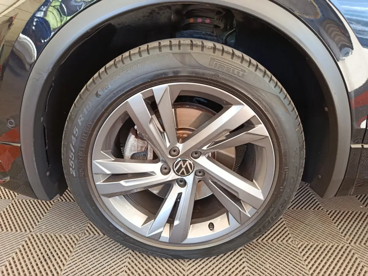 Gros plan sur la roue avant droite du Volkswagen Tiguan noir, jante alliage moderne à plusieurs branches.