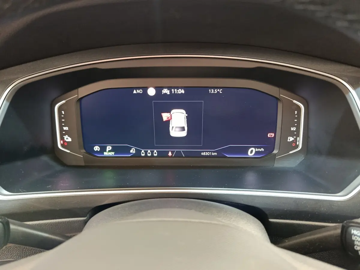 Vue rapprochée du tableau de bord numérique du Volkswagen Tiguan noir, affichant une porte ouverte et 48 301 km au compteur.