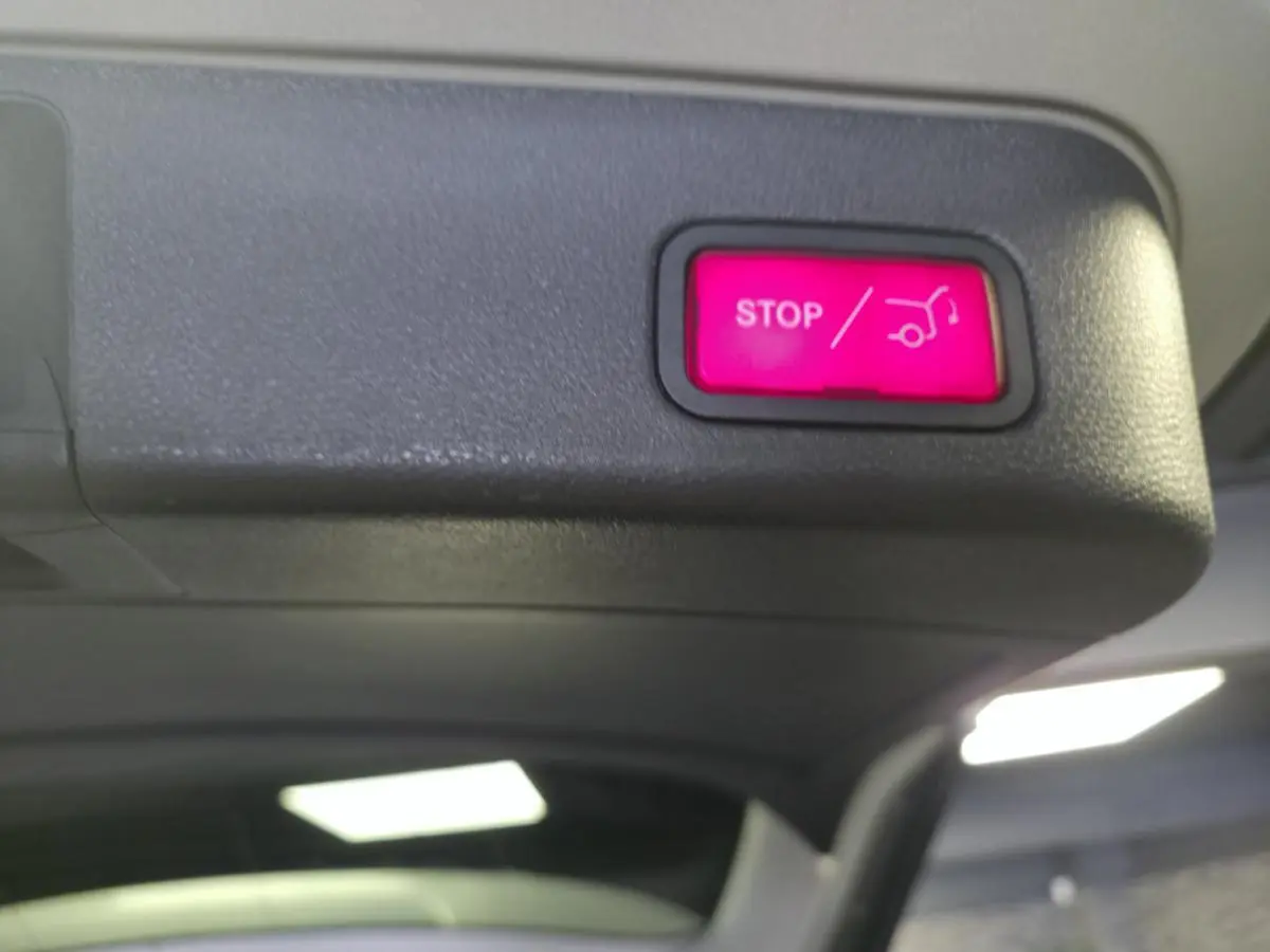 Bouton rouge d'ouverture/fermeture électrique du hayon sur le coffre d'un Mercedes Classe M gris.