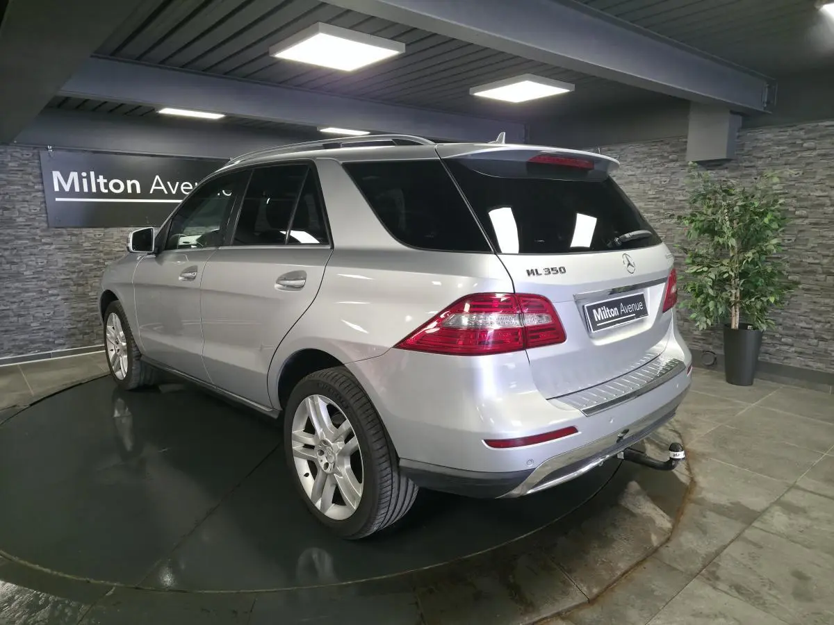 Vue 3/4 arrière droite d'un Mercedes Classe M ML 350 BlueTEC gris métallisé avec attelage et vitres teintées.