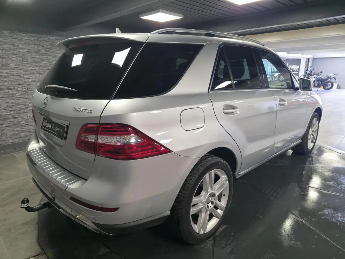 Vue 3/4 arrière droit d'un Mercedes Classe M gris métallisé avec attelage démontable et vitres arrière teintées.