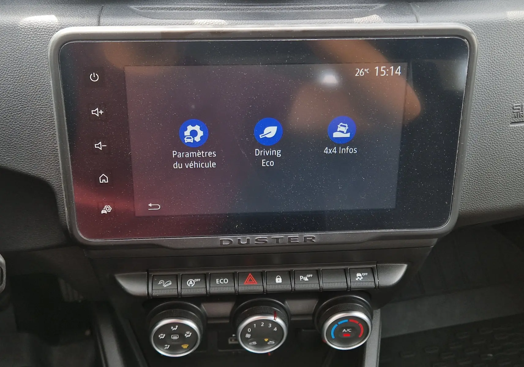 Écran tactile central du tableau de bord du Dacia Duster 2023 avec affichage des paramètres véhicule et commandes climatisation.