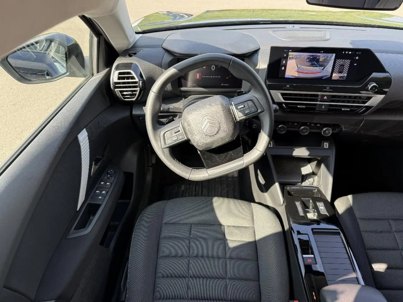 Vue intérieure de face du poste de conduite de la Citroën C4 2025, avec volant multifonction et écran tactile central.