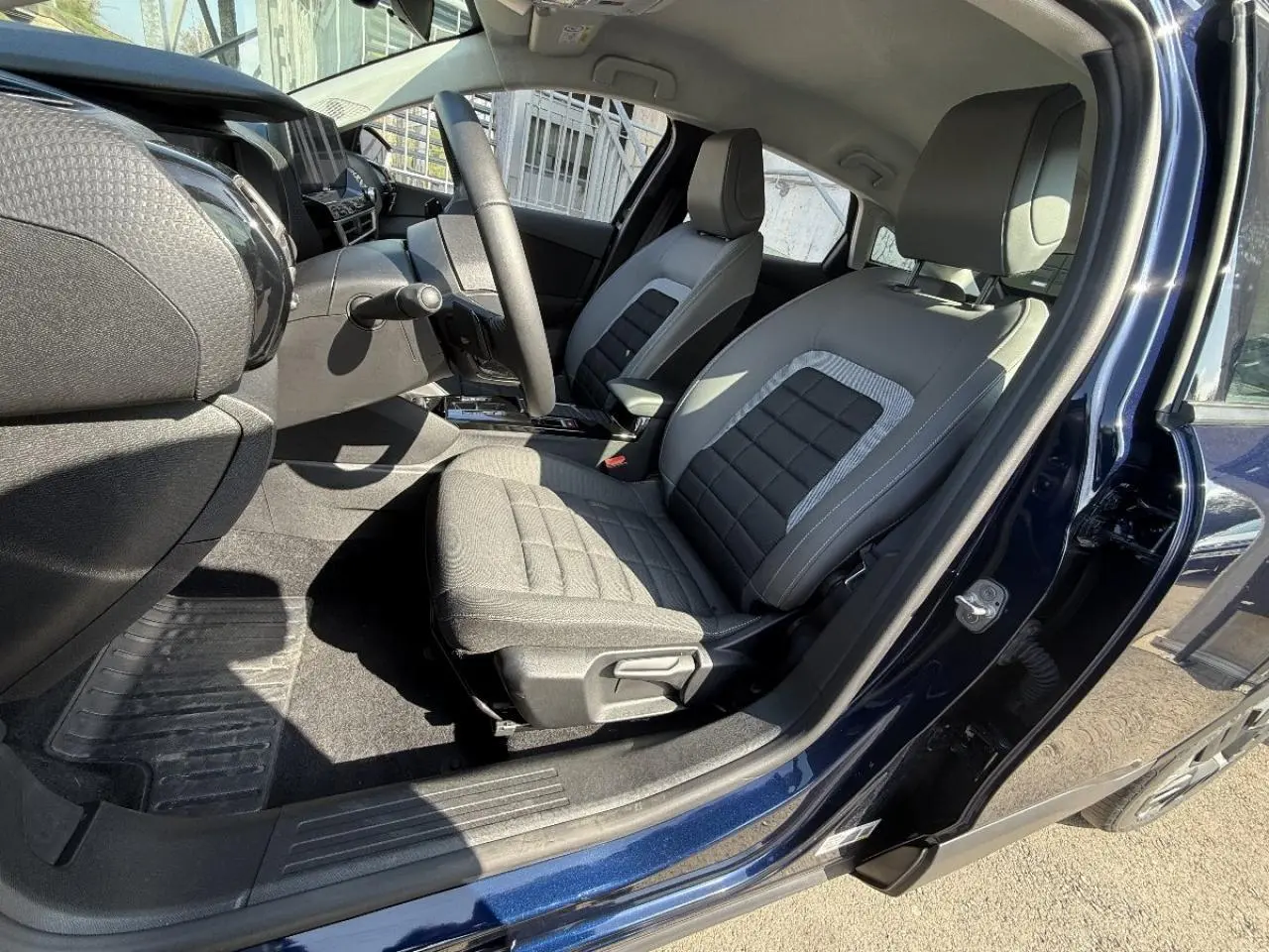 Vue intérieure côté conducteur de la Citroën C4 2025 en new dark blue, montrant les sièges gris et le tableau de bord moderne.