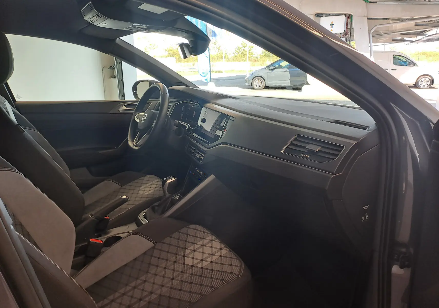 Vue intérieure côté conducteur du Volkswagen Taigo gris cendre 2025, avec sièges tissu à motifs et tableau de bord moderne.