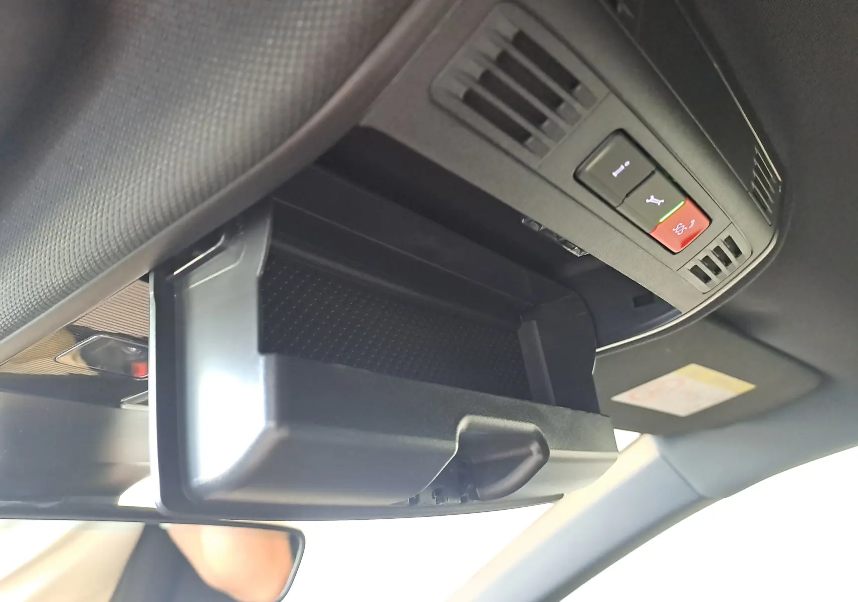 Rangement lunettes ouvert au plafond intérieur d’un Volkswagen Taigo gris cendre, avec commandes d’assistance visibles.