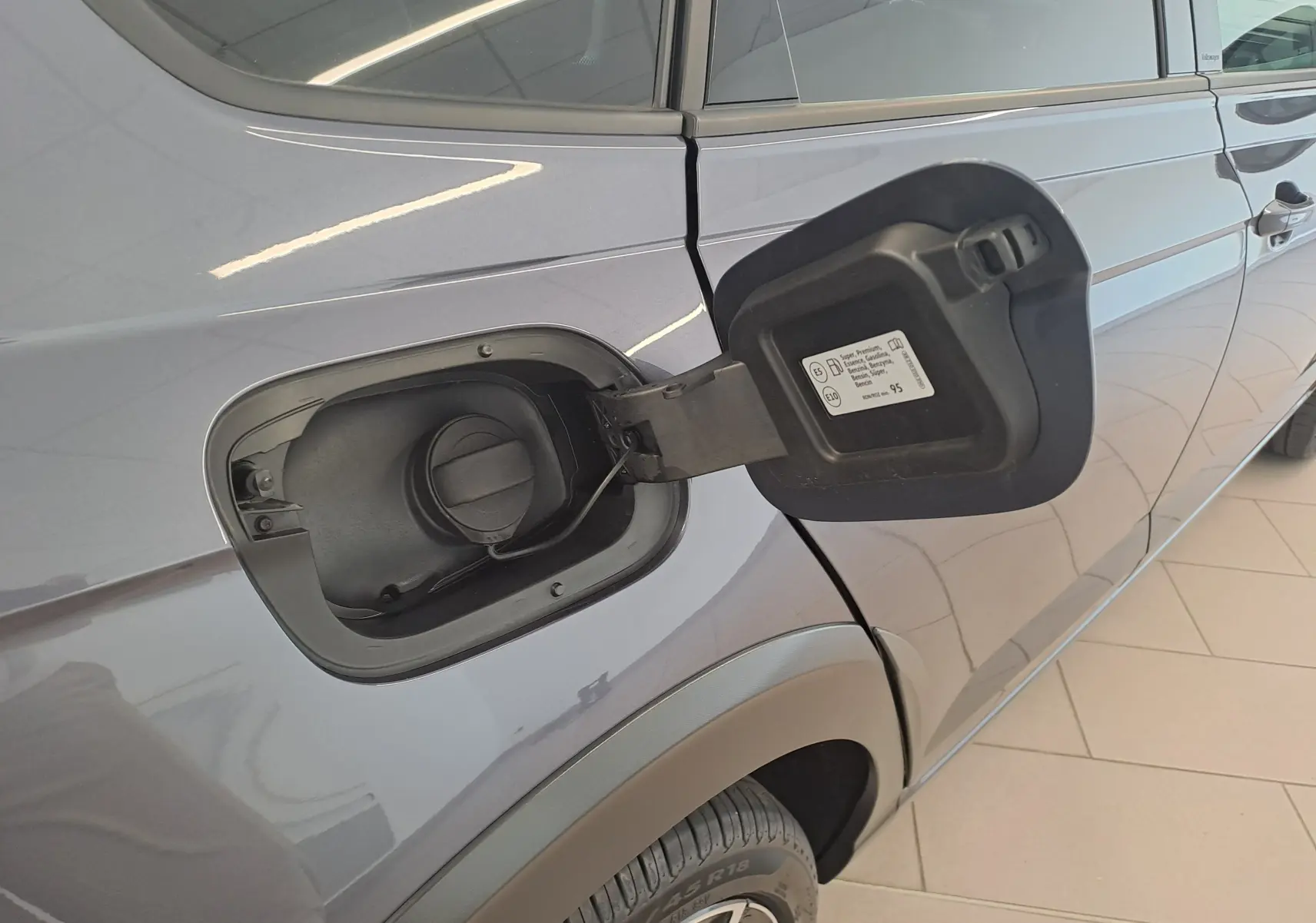 Vue latérale droite du Volkswagen Taigo gris cendre 2025, avec trappe à carburant ouverte et jante alliage 18 pouces visible.