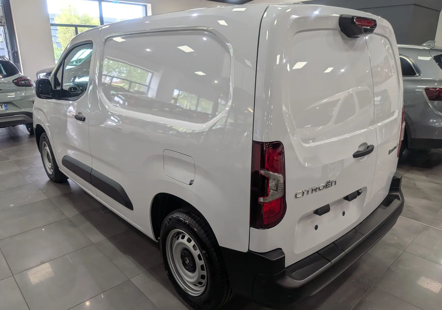 Vue 3/4 arrière droite du Citroën Berlingo Van blanc 2025 avec portes arrière pleines et protections noires.