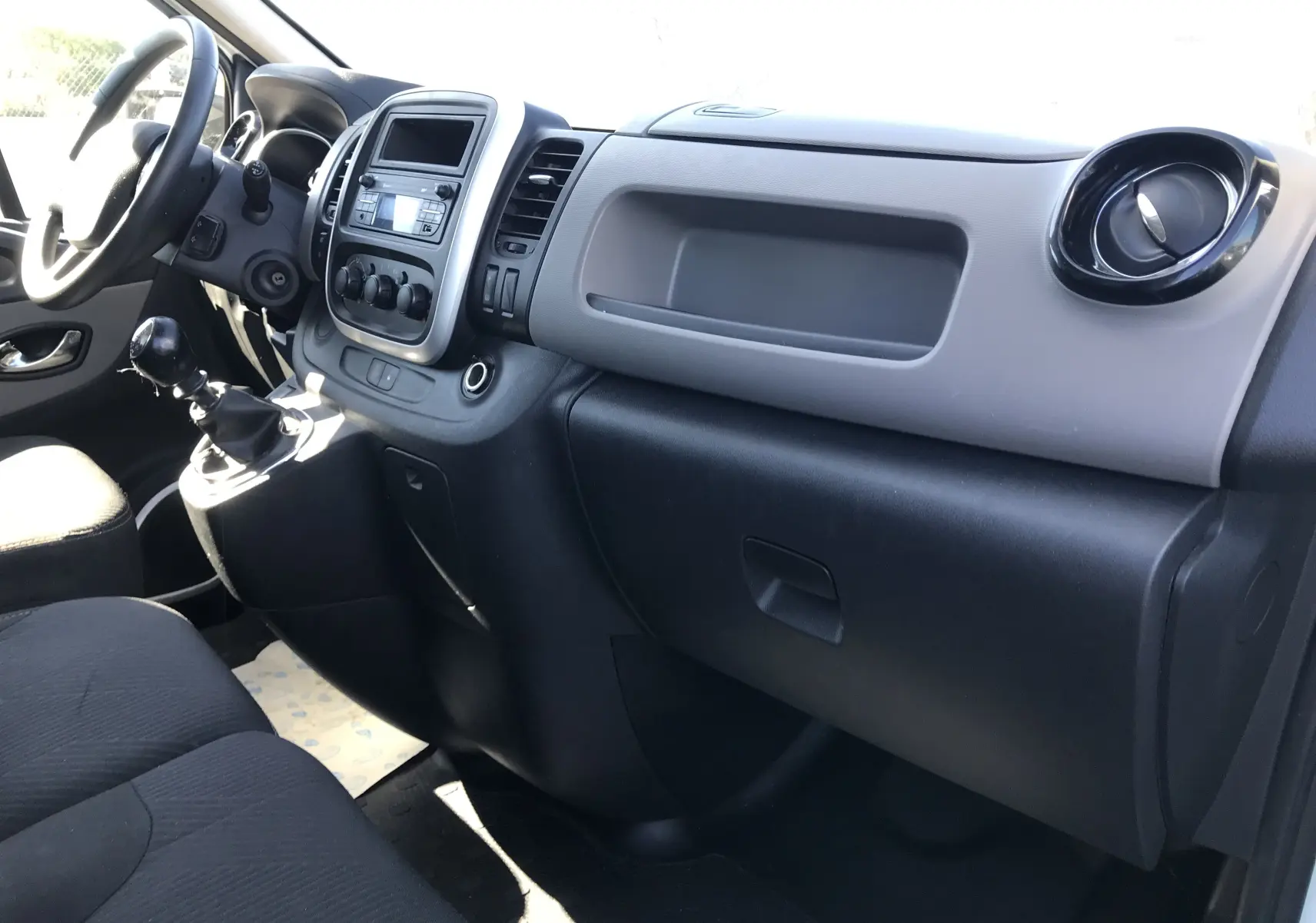 Intérieur côté passager du Renault Trafic Fourgon blanc 2017, tableau de bord et levier de vitesses manuelle visibles.