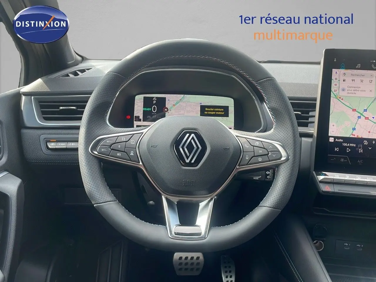 Vue centrée sur le volant en cuir noir perforé du Renault Captur E-Tech 2025 avec tableau de bord numérique et écran tactile.