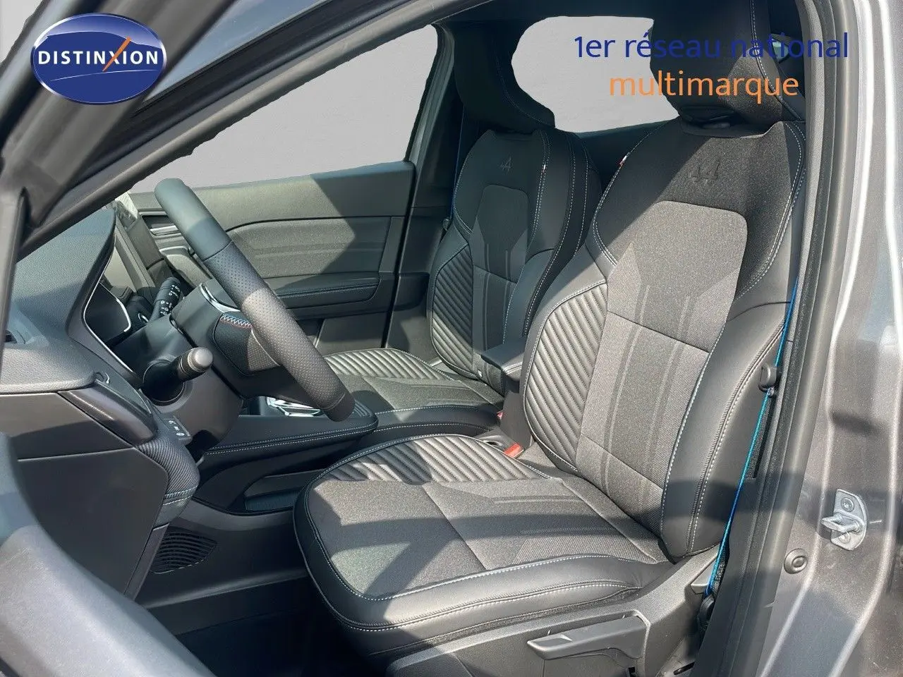 Intérieur avant droit du Renault Captur E-Tech gris cassiopée, sièges noirs avec surpiqûres et logo Alpine brodé.