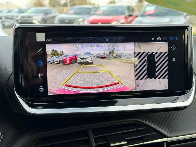 Écran tactile montrant la caméra de recul avec vue arrière d’un véhicule rouge et d’une Peugeot 2008 blanche en face.